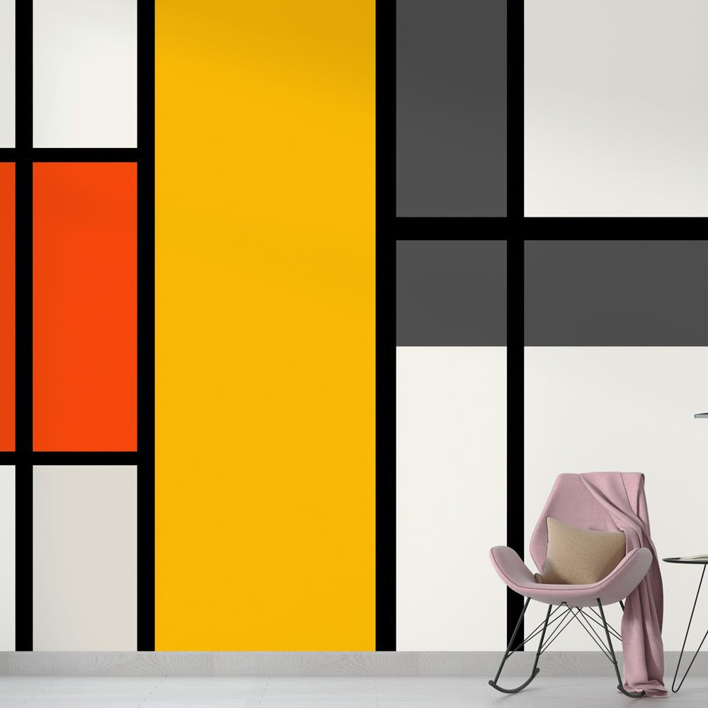 Modern geometric mural wallpaper in Mondrian style with yellow and orange blocks, shown with pink accent chair