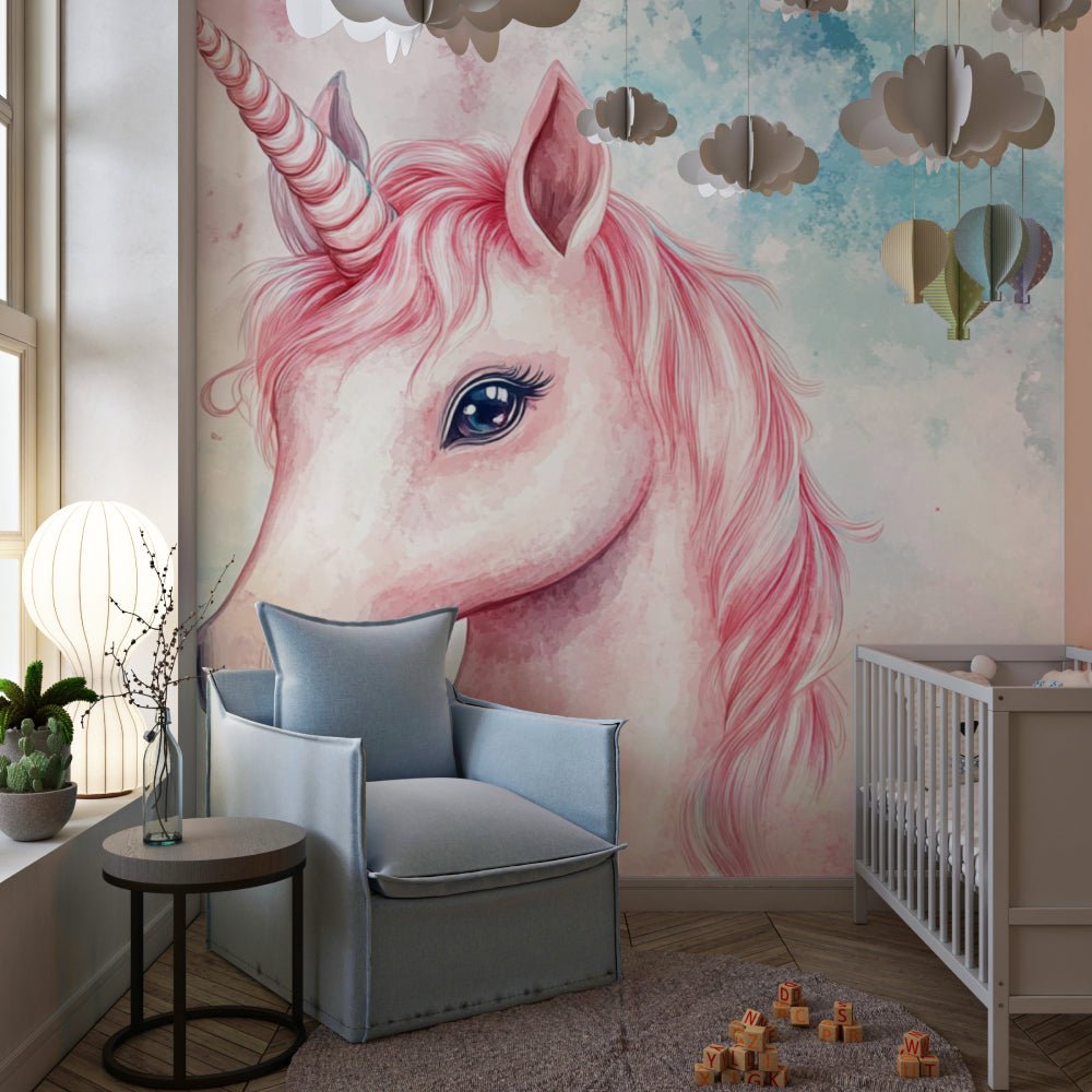 Pink unicorn watercolor mural wallpaper in a modern nursery with gray armchair and cloud decorations