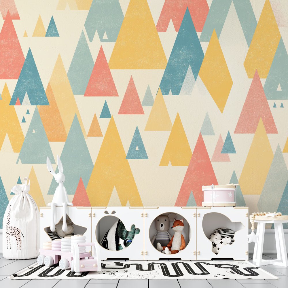 Modern geometric mountain mural wallpaper in pastel colors shown in a children's room with white furniture and toys